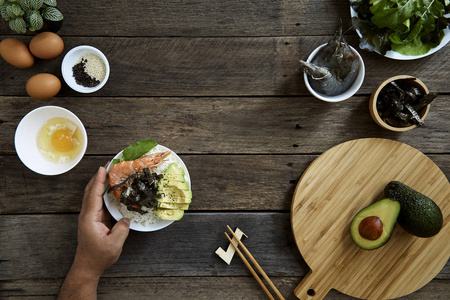 虾生鱼片米戳碗与鳄梨清洁平衡的健康食品概念。深色木制背景，俯视图像。