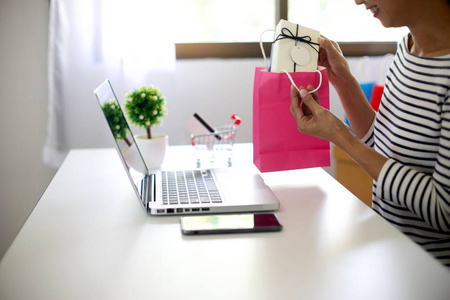 女人坐在电脑桌前看产品包装打开或包装主题购物网上销售和购买订单