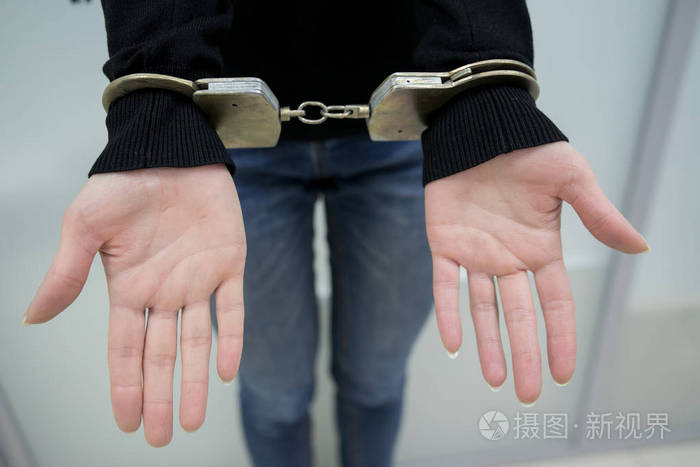照片 特写镜头.被逮捕的人用手铐将双手铐在灰色背景上背部.