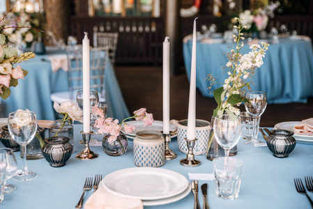 在蓝色桌布上的银色烛台上装饰着鲜花和蜡烛的节日餐桌