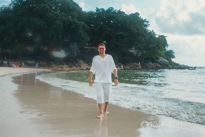 海滩背景上戴眼镜的帅哥一个穿白色衣服的人的肖像