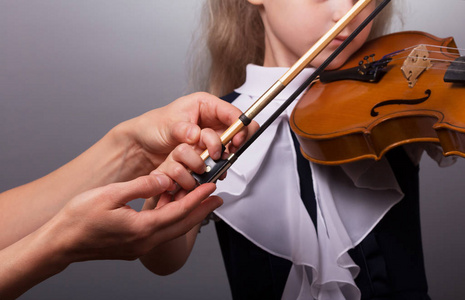 学习拉小提琴。 小女孩和老师拉小提琴