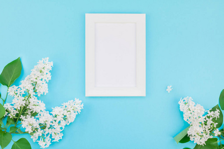 创意平躺概念顶部视图空白明信片框架模拟和白色丁香花花瓣在粘贴蓝色背景与复制空间在最小风格模板的文字或设计