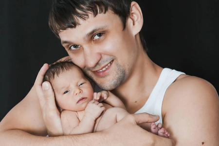 新生婴儿躺在父母手上的黑色背景上。 父亲和达赫特。 男人对孩子的爱的表现