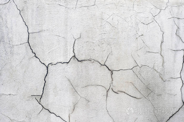 有卷曲裂缝的旧房子的白色混凝土墙背景