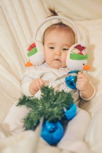 一个戴着耳机的小孩，脸上堆着雪人，玩着蓝色的圣诞球