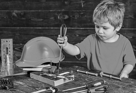集中的儿童装订螺丝到木板。金发男孩玩工具设置。学前儿童学习新技能