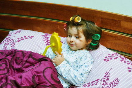 躺在床上的卷发小女孩的肖像。 晨间小时尚