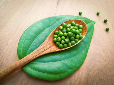 木勺上的新鲜青椒种子和胡椒科的绿叶或木底胡椒的胡椒照片