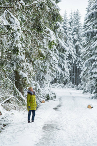 一个年轻的女人正在白雪覆盖的树木之间穿过冬林