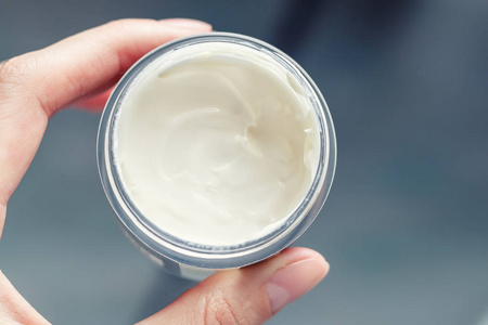 s hand holding a jar of cream