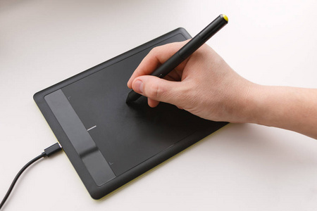 s hand draws on a graphics tablet using a stylus