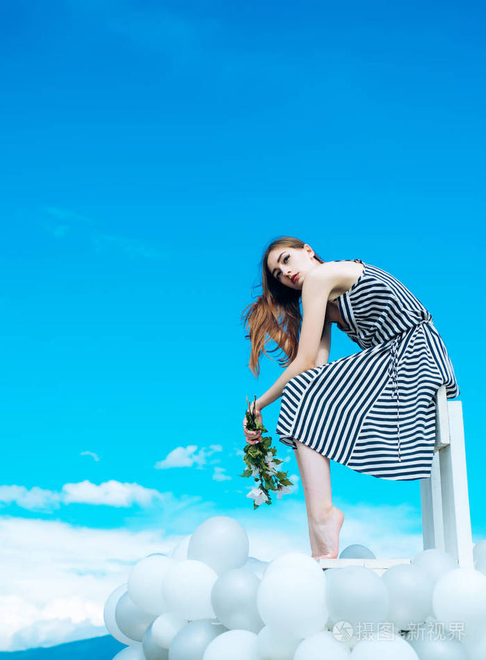 有花的女孩坐在天空中.灵感和想象力.感觉自由和梦想.时尚的女人肖像.
