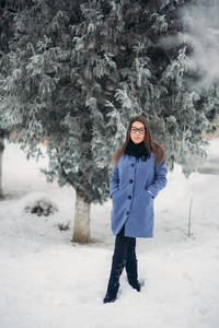 美丽的女孩在户外的冬天。女孩被白雪覆盖的树木包围着。圣诞节的气氛。新的一年