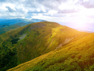 夏季山区景观。 绿色的草地。 高高的山丘。 日落