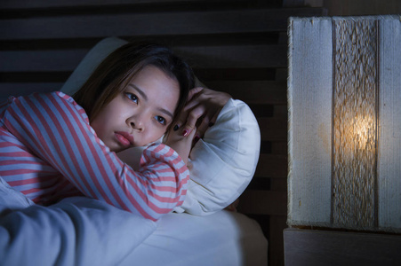年轻美丽悲伤沮丧的亚洲女孩深夜躺在床上，睡不着觉，陷入沉思，失眠，睡眠障碍，疲劳和焦虑，女人抑郁的概念