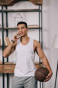 英俊的两族男人拿着篮球在智能手机上说话
