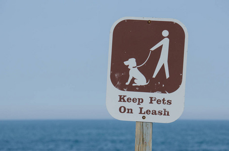 告示牌警告公园和海滩游客把宠物拴在皮带上