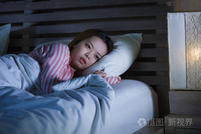 年轻美丽悲伤抑郁的亚裔韩国女孩深夜躺在床上睡不着觉陷入沉思失眠