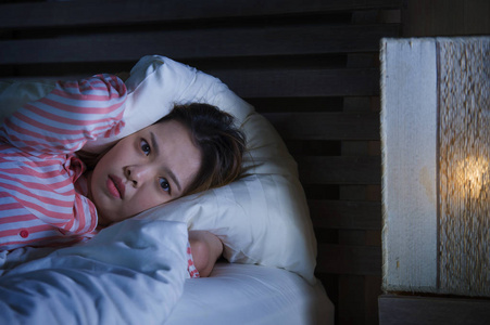 概念可爱的失眠小女孩躺在床上,闹钟看起来很累,有睡眠问题,晚上睡觉