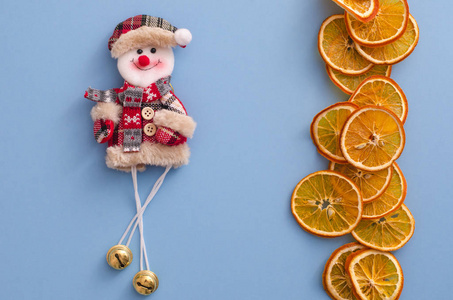 干片橘子柑橘水果和有趣的雪人在浅蓝色背景。 自制天然香气装饰。 假期的概念。 结婚圣诞。 近距离平躺俯视