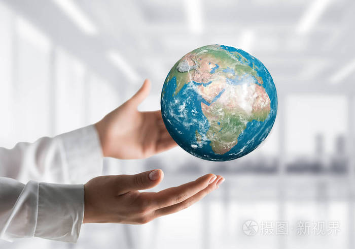 侧视特写的商人在衬衫上手握地球仪与办公室的背景.