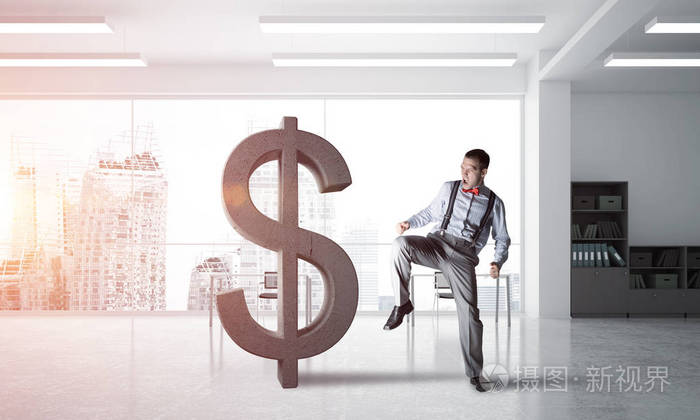 年轻暴怒的商人将用踢石美元符号崩溃照片-正版商用图