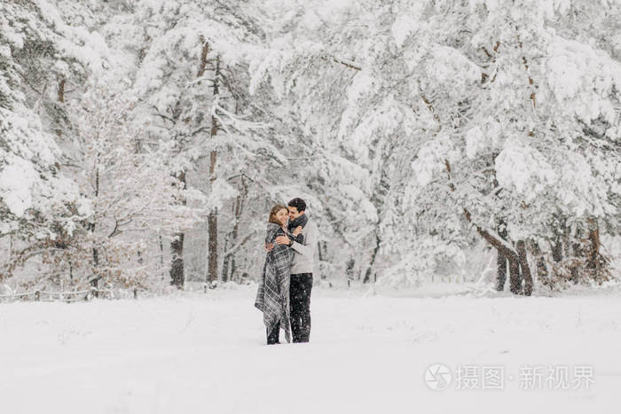 一对相爱的夫妇在雪地森林里拥抱亲吻和享受