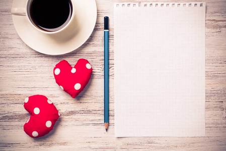 咖啡杯记事本铅笔，两颗红心在木制表面