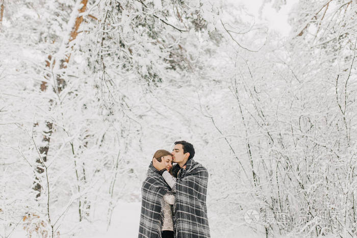 恋爱中的情侣走在雪地森林里拥抱亲吻和享受