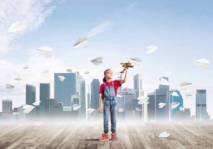 可爱的小女孩站在木地板上,纸飞机飞来飞去