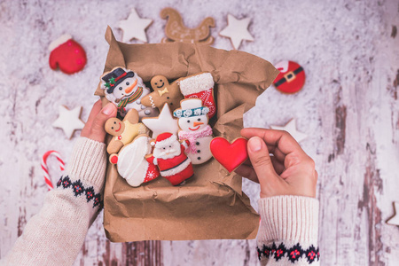 木制背景上的圣诞礼物姜饼。 节日包装中的饼干。 女人正在一个盒子里包装圣诞姜饼饼干。 上面的风景。 复制空间