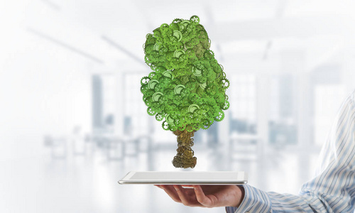 接近商人持有平板电脑与绿色树由齿轮和齿轮. 混合媒体照片