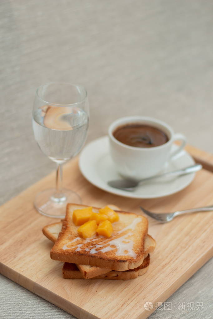 一杯白杯咖啡,一杯水,一杯芒果和炼乳吐司