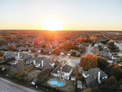 鸟瞰住宅区附近的公路与交通在秋季日落在花丘德克萨斯州美国。 一排有游泳池和五颜六色叶子的独栋别墅