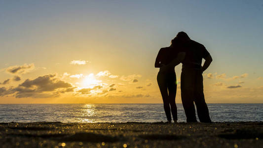 一对夫妇的剪影在海滩上与一个美丽的日落背景