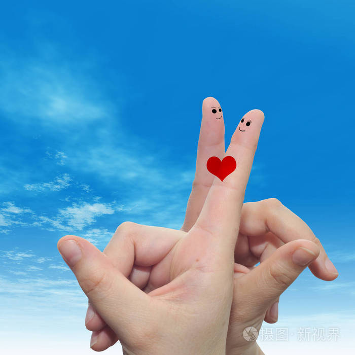 概念或概念人类或女性的双手,用两个手指涂着红色的心,在云蓝色的天空