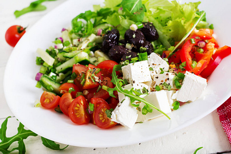 健康的食物。 希腊沙拉新鲜黄瓜，番茄，甜椒，生菜，洋葱，FETA奶酪和黑橄榄与橄榄油。 佛碗。