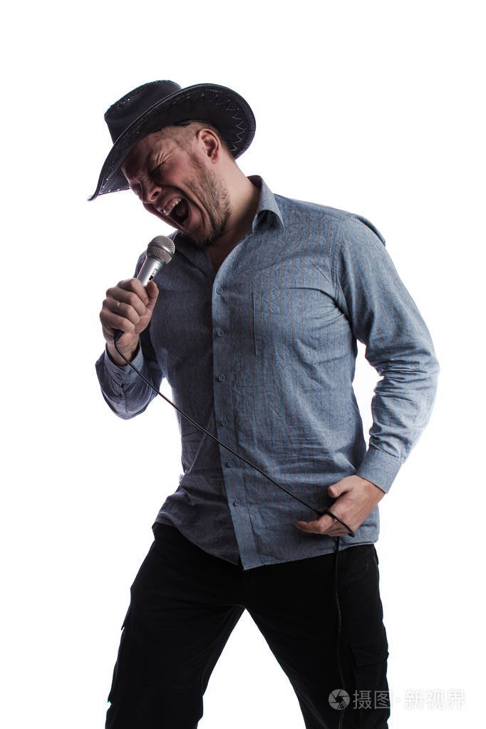 一个情绪激动的演员,穿着灰色衬衫,戴着黑色帽子,手里拿着麦克风,在