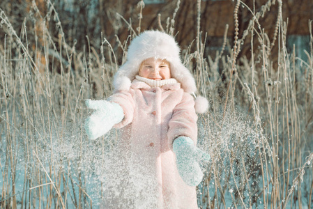 冬天公园外面穿着粉红色外套的小可爱的微笑女孩扔雪