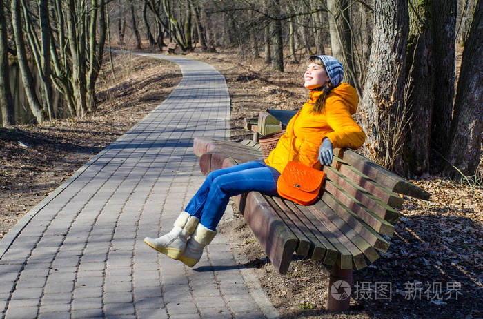 穿着橙色夹克的女人在公园散步