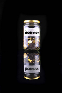 带有黑色背景的标签保险的瓶子里的硬币财务概念