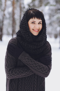 冬雪森林里穿着毛衣的年轻美丽的黑发女孩
