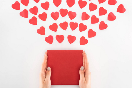 在白色情人节的概念上，在十几个红色的心脏符号下抱着信封的女人剪下的照片