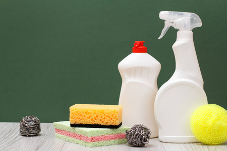 塑料瓶的洗碗机液体玻璃和瓷砖清洁剂和海绵在绿色背景。 洗涤和清洁的概念。