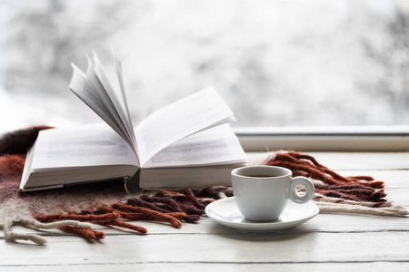 一杯咖啡, 用温暖的格子打开了书, 在白色的窗台上, 从外面的雪景