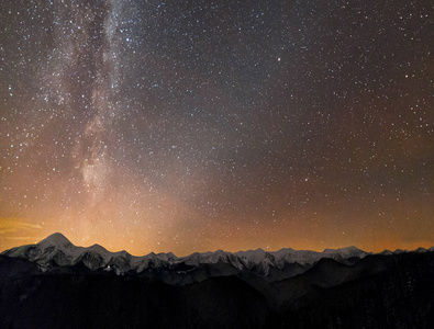 冬山夜景全景。 银河明亮的星座在黑暗的星空下，夕阳后，地平线上柔和的光芒，壮丽的山脊，白雪覆盖的山峰，白雪覆盖的陡峭的木本小山。