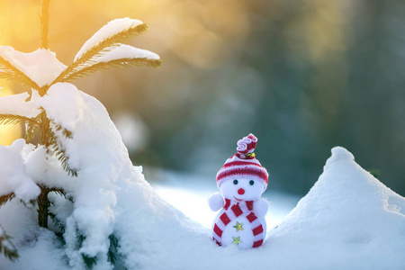 小有趣的玩具婴儿雪人在针织帽子和围巾在深雪户外明亮的蓝色和白色复制空间背景。 新年快乐，圣诞贺卡快乐。