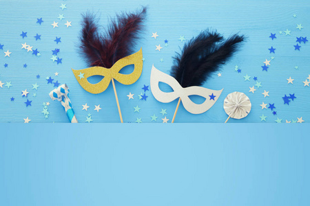 嘉年华派对庆祝概念与优雅的黄金面具上的棍子蓝色木制背景和明星。 顶部视图