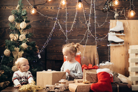愉快的小孩在圣诞老人帽子与礼物有圣诞节。冬天的晚上在家里。圣诞节和新年的开幕礼物。圣诞快乐, 新年快乐。孩子们圣诞节